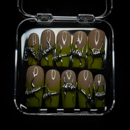 A set of 10 press-on nails displayed in a clear plastic case against a black background. The nails feature a nude-to-chartreuse green gradient base with a metallic silver barbed wire wrapped around the center of each nail.